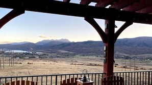 A wooden deck with a table and chairs, overlooking a valley with mountains in the distance. - Gorgeous 5 bedroom 4.5 bath home with incredible mountain and lake views. (Eden)