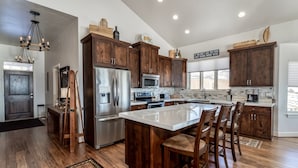 A modern kitchen with wooden cabinets, stainless steel appliances, and a large island with bar stools. - Gorgeous 5 bedroom 4.5 bath home with incredible mountain and lake views. (Eden)
