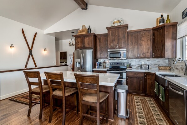 Una cocina moderna con armarios de madera, electrodomésticos de acero inoxidable y un comedor con mesa y sillas.