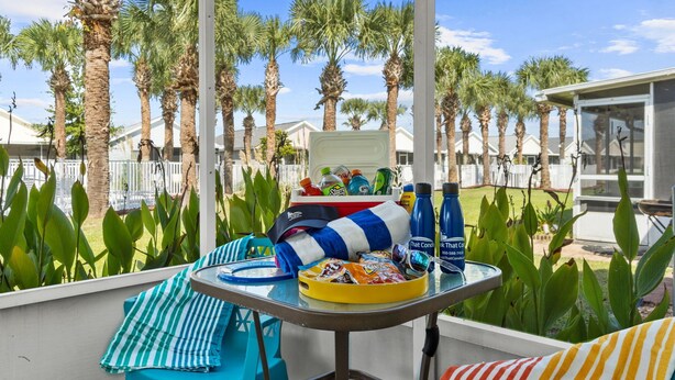 A balcony with a table set for a meal, surrounded by palm trees and a view of other buildings.