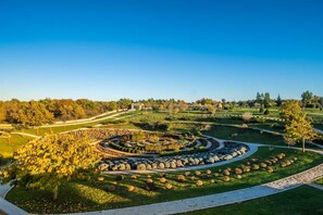 Ein angelegter Park mit einem kreisförmigen Steinbrunnen, Wegen und verschiedenen Bäumen und Sträuchern.