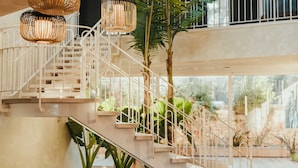 Un escalier avec des rampes blanches et un plancher en bois, entouré de verdure et offrant une vue sur l’extérieur.