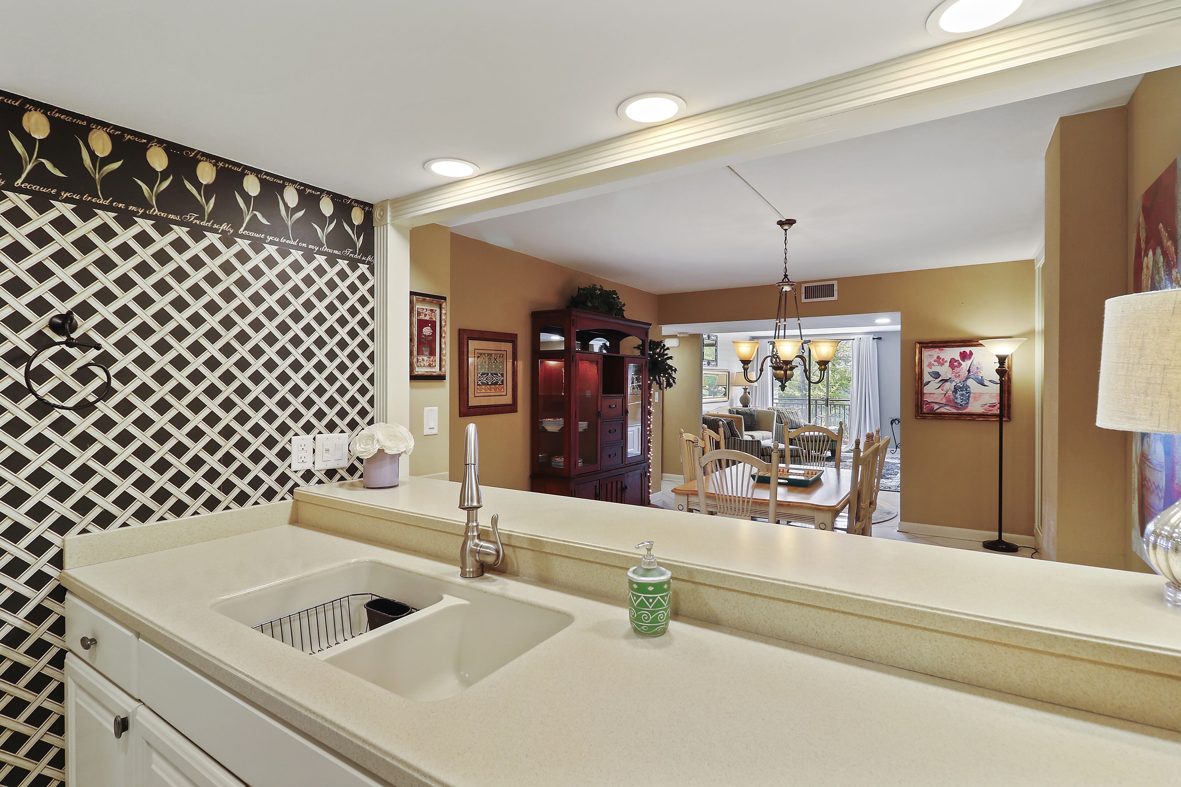 A kitchen with a large mirror, a sink, and a patterned backsplash.