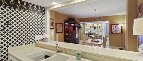 A kitchen with a large mirror, a sink, and a patterned backsplash.
