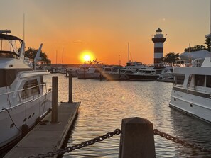 A marina with boats docked at wooden piers during sunset.