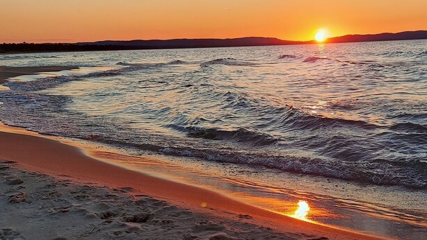 Une plage avec des vagues au coucher du soleil.
