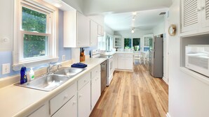 Une cuisine moderne avec des armoires blanches, des appareils en acier inoxydable et un plancher en bois.