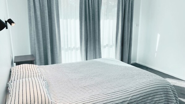 A hotel room with a bed, a nightstand, and a lamp.