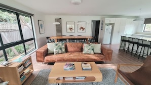 Ein modernes Wohnzimmer mit braunem Sofa, Couchtisch und Essbereich mit Holztisch und Stühlen.