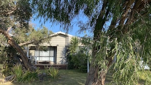 Ein modernes Haus mit überdachter Terrasse, umgeben von üppiger Vegetation und Bäumen.