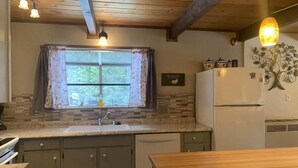 A kitchen with a wooden ceiling, a window with curtains, a refrigerator, and a sink. - 4 bdrm 2 bath - sleeps 10 living & family room space for everyone! Dogs okay. (Arnold)