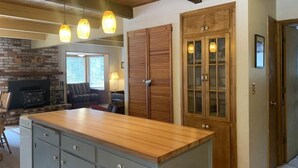 A kitchen with a wooden island, a brick wall, and a fireplace. - 4 bdrm 2 bath - sleeps 10 living & family room space for everyone! Dogs okay. (Arnold)