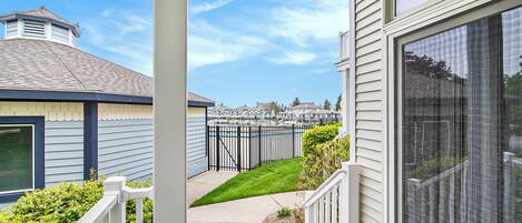 A residential property with a covered porch, a fenced yard, and a view of neighboring houses.