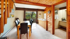 Un interior de madera con comedor, cocina y vistas al exterior.