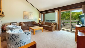 Una sala de estar con sofá, sillones, una mesa de centro y televisor.