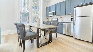 Una cocina moderna con una mesa de comedor y sillas, un refrigerador de acero inoxidable y armarios azules.