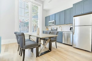 Una cocina moderna con una mesa de comedor y sillas, un refrigerador de acero inoxidable y armarios azules.