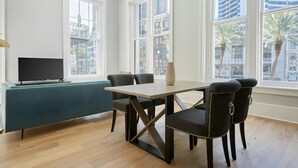 Una sala de estar moderna con televisor, sofá color turquesa y una mesa de comedor con cuatro sillas.