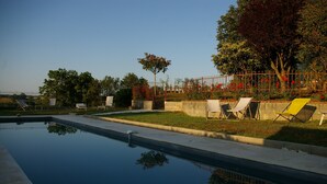 Una piscina con lettini e una zona giardino.