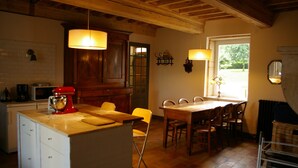 Una cucina con mobili in legno, un frullatore rosso, un tavolo da pranzo con sedie e una finestra che lascia entrare luce naturale.