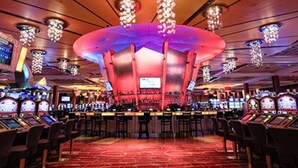 Een casino met gokautomaten, een bar en een grote kroonluchter.