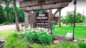 Een houten bord met daarop Barley Creek Brewing Company, met een bord voor een Growler-aankoppelstation eronder.