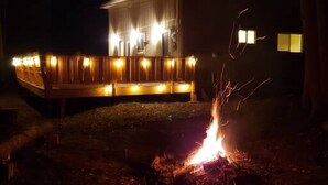 Een gebouw met een overdekt terras en een verlichte vuurkorf.