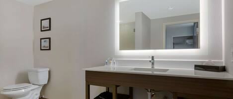 A modern bathroom with a white toilet, a vanity with a mirror, and a sink.