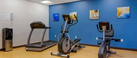 A gym with treadmills, elliptical machines, and dumbbells.