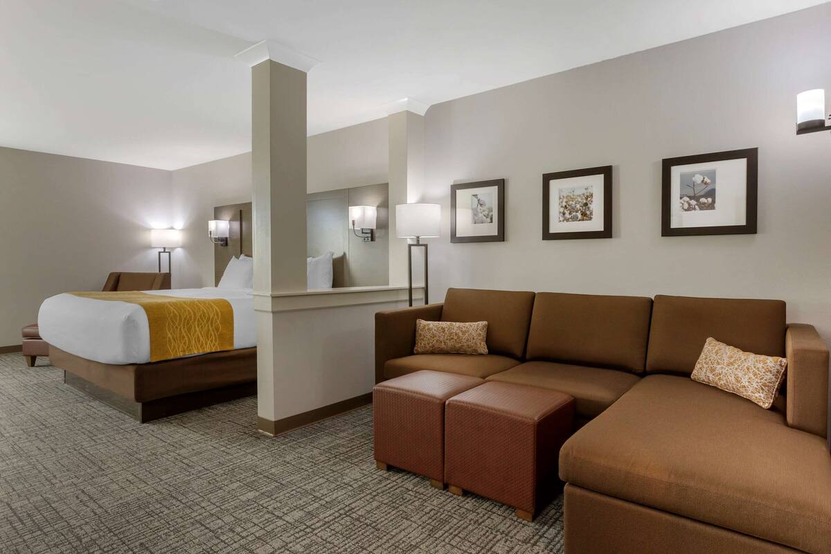 A hotel room with a bed, a sofa, a coffee table, and wall-mounted lamps.