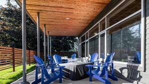 Un patio al aire libre con zona de estar cubierta, una mesa y sillas.
