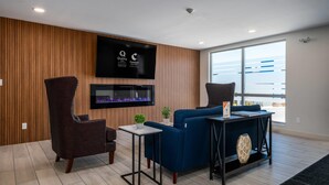 Una sala de estar moderna con un televisor de pantalla plana, un sofá azul, un sillón oscuro y una mesita auxiliar.