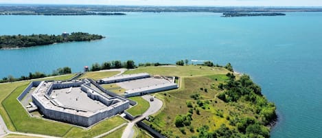 An aerial view of a fort with a large courtyard, surrounded by water and greenery.