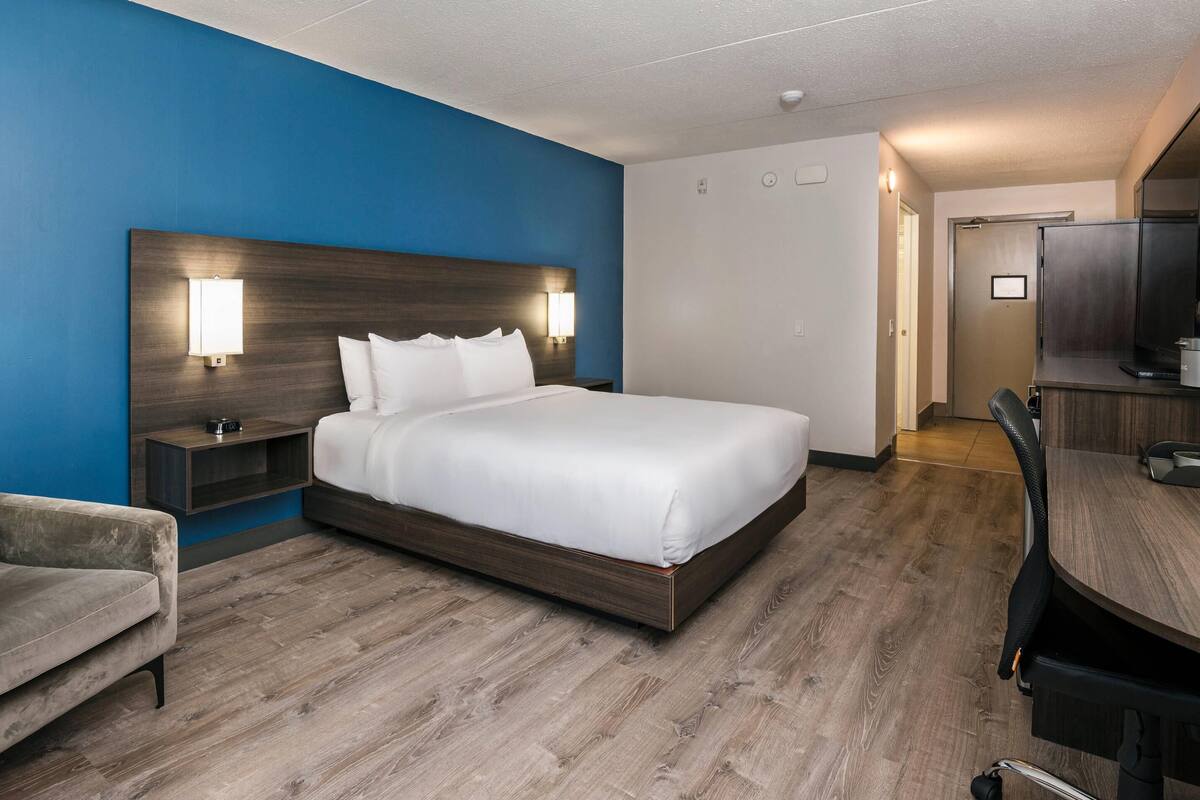 Una habitación de hotel con una cama grande, un escritorio y una silla.