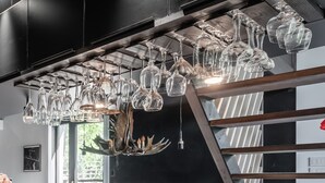 Un candelabro con múltiples copas de vidrio para vino colgadas de una viga de madera.