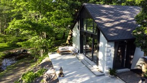 Una casa moderna con fachada de vidrio, un sendero de piedra y un estanque.