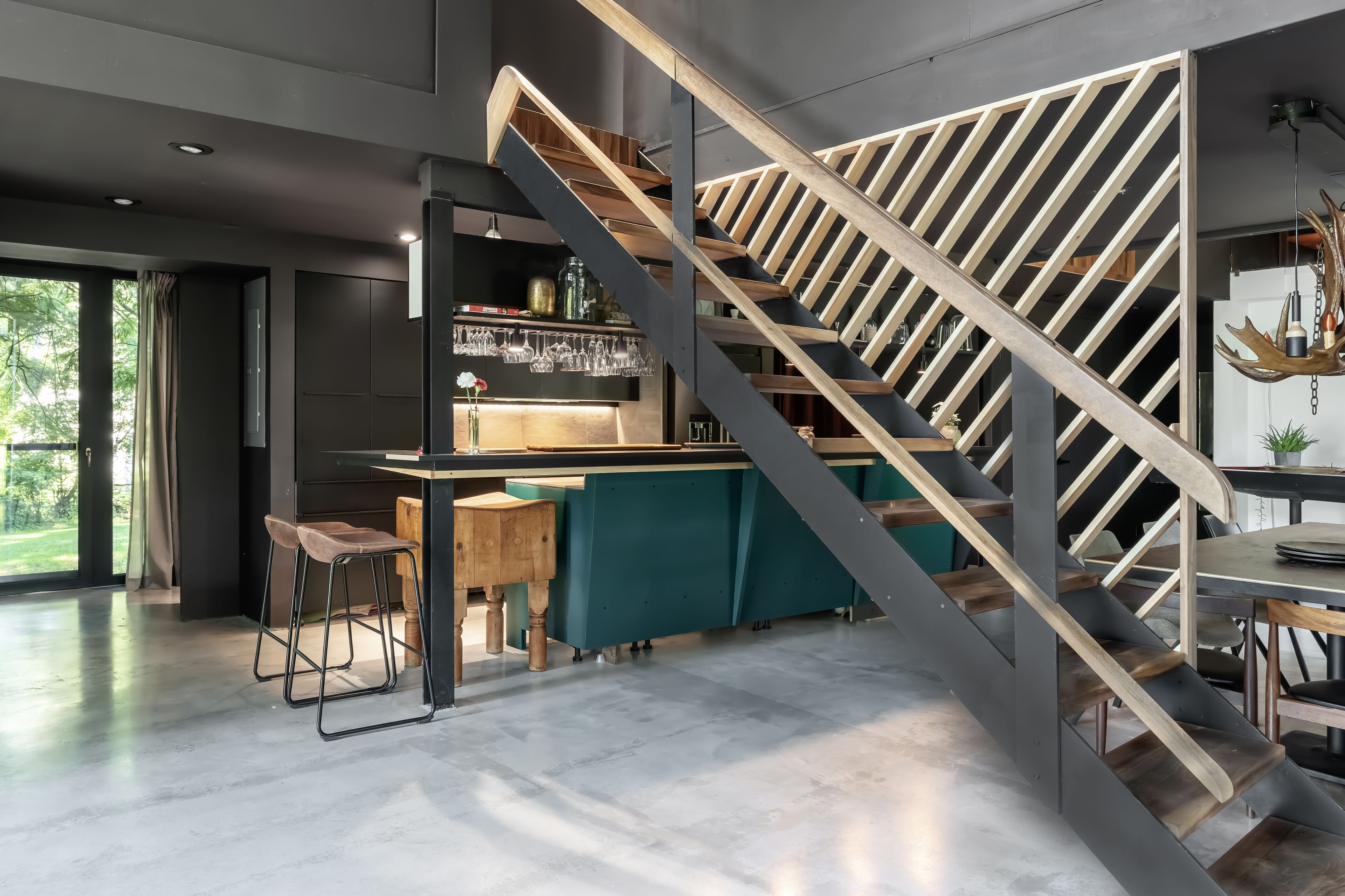 Une cuisine moderne dotée d’un bar intégré, d’un escalier avec des marches en bois et offrant une vue sur l’extérieur.