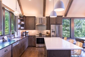 A modern kitchen with a central island, stainless steel appliances, and a view of the outdoors. - Lucky Landing - BRMC amenities, pets, views, hot tub, fire pit, game tables (Boone)