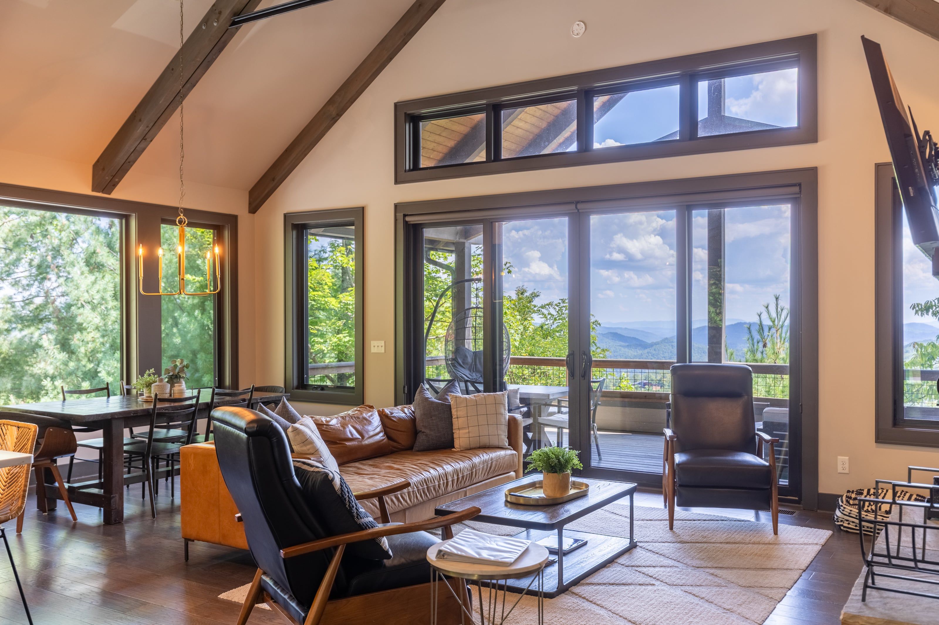 A spacious living area with a high ceiling, large windows, and a view of the outdoors.
