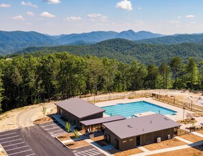 A hotel with a swimming pool, parking, and a view of mountains.