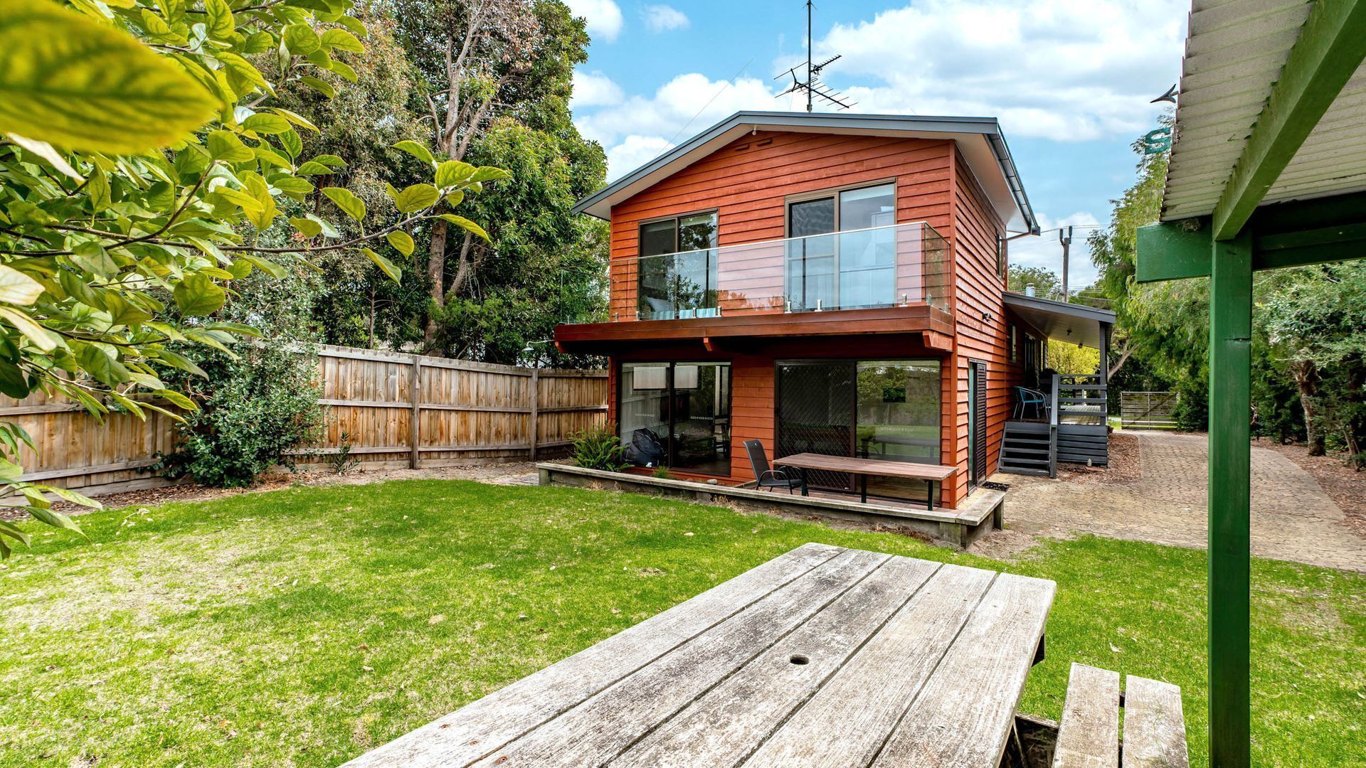 A modern two-story house with a wooden deck and a patio table.