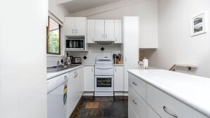 A compact kitchen with white cabinets, a stove, a microwave, and a sink. - WAVELENGTH - Free Wifi and Pet Friendly (outside only) (Inverloch)