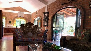 A spacious lobby with a brick wall, a glass coffee table, and a sofa with patterned cushions.
