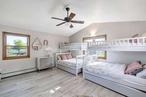 A bedroom with bunk beds, a ceiling fan, a bedside table, and a window with a view. - Waterfront Haven! Kayaks Included w/Hot Tub (Green Bay)
