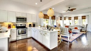 A spacious kitchen with white cabinetry, a central island, and a dining area with a patterned rug. - Luxury Townhouse with rooftop view of downtown! (Nashville)