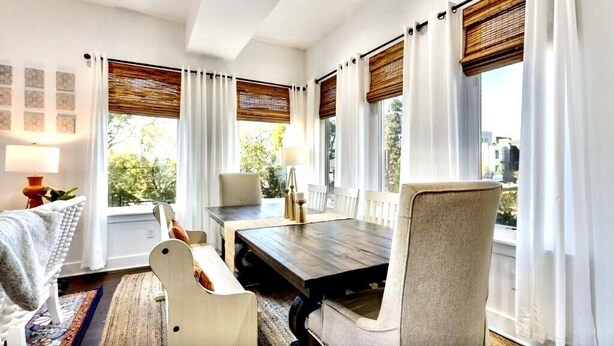 A dining area with a wooden table, white chairs, and a view of greenery outside. - Luxury Townhouse with rooftop view of downtown! (Nashville)