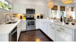 A modern kitchen with white cabinetry, stainless steel appliances, and a central island. - Luxury Townhouse with rooftop view of downtown! (Nashville)