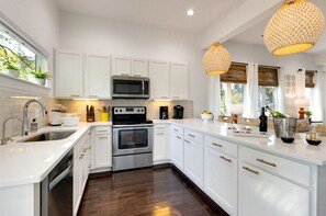 A modern kitchen with white cabinetry, stainless steel appliances, and a central island.