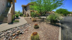 Un quartiere residenziale con una casa caratterizzata da facciata in pietra, una scala e un giardino con cactus e un albero.
