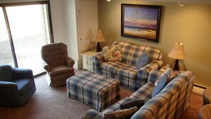 A living room with a sofa set, armchairs, and a coffee table. There is a painting on the wall and a lamp on the side table. - 2King Master Suites, Walk to golf, Outside heated pool (Cedar)